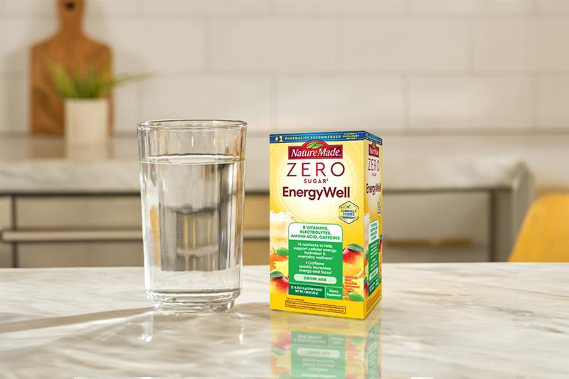 Nature Made Zero Sugar EnergyWell Drink Mix next to a glass of water on a kitchen counter.