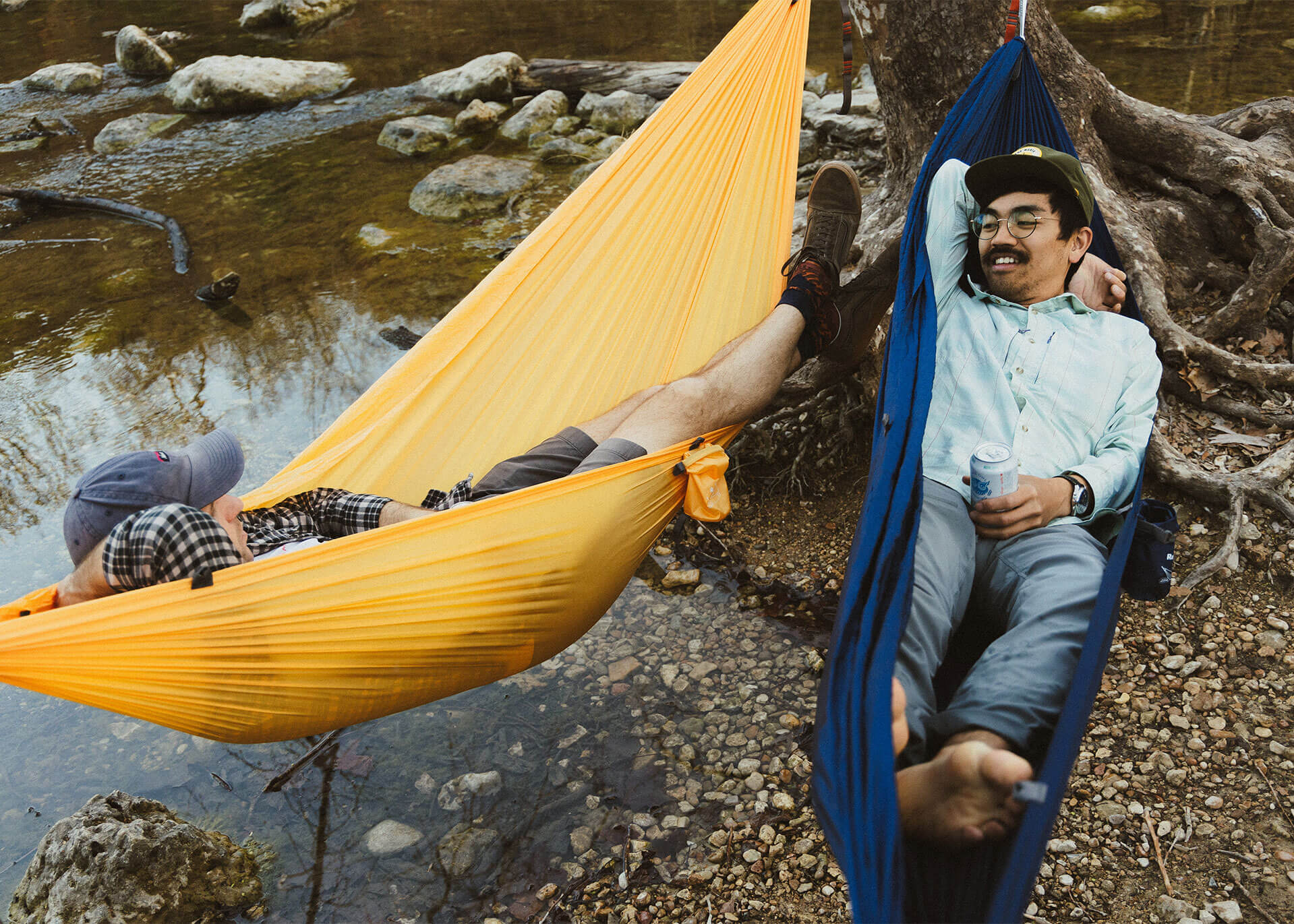 Men lounging in Kammok Roo Singles camping hammock in Midnight Blue and Sunflower Gold.