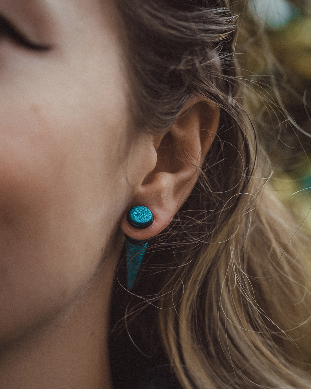 Goth woman wearing  Turquoise Glitter Fake Taper / Plug / Gauge