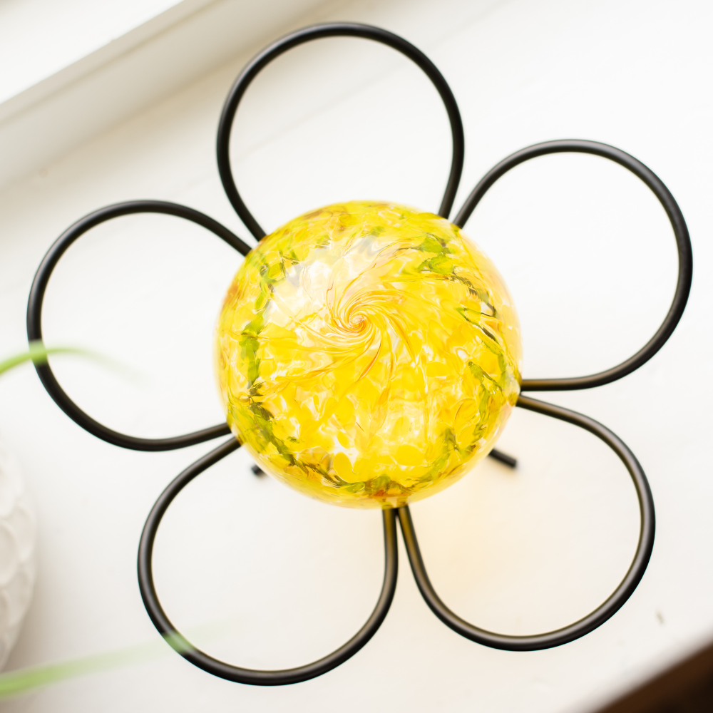 Bright Yellow Nature's Whimsy Orb on a Five Petal Garden Holder. Displayed on a while window sill. 