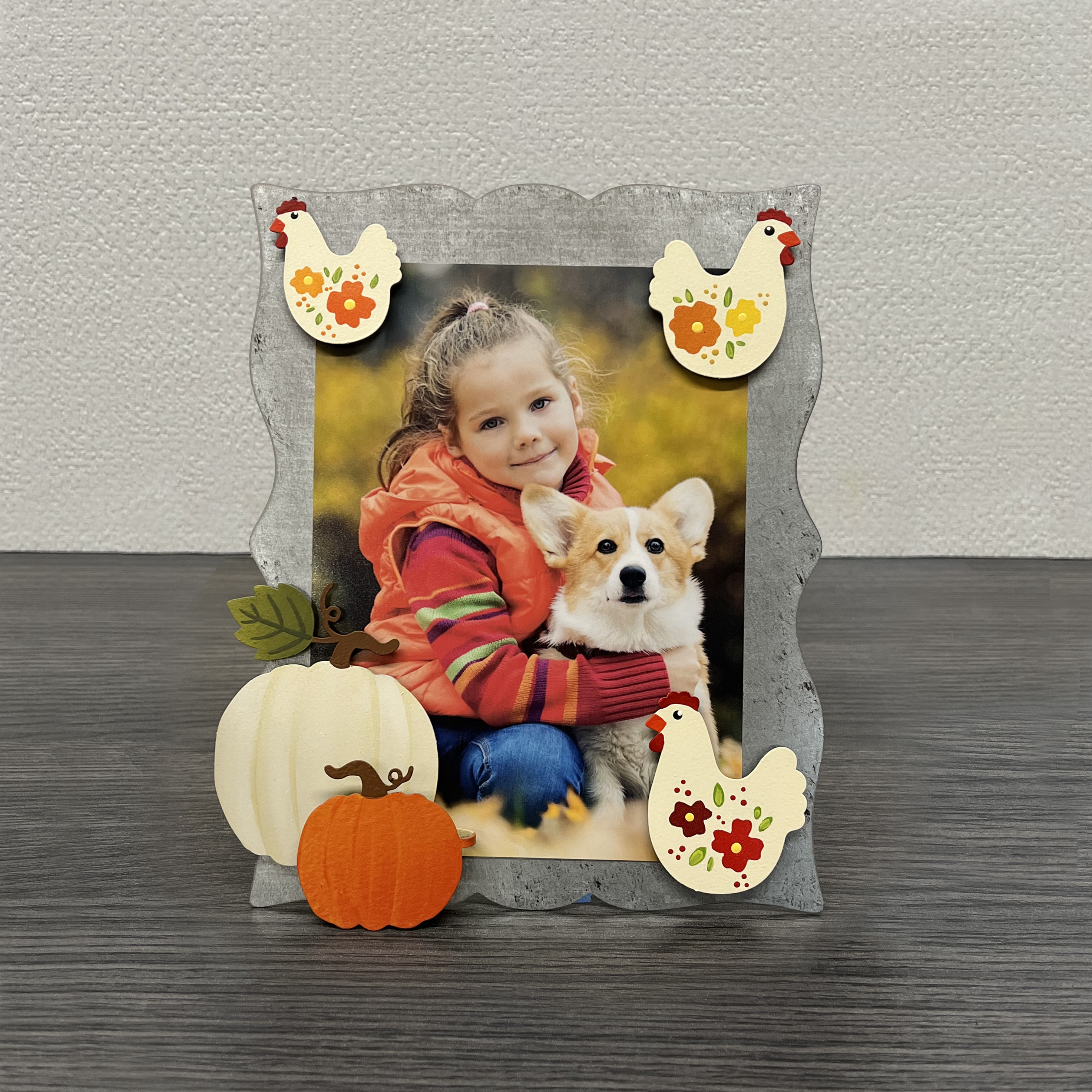 Metal easel with pumpkins and hen magnets and photo of a girl with a dog. 