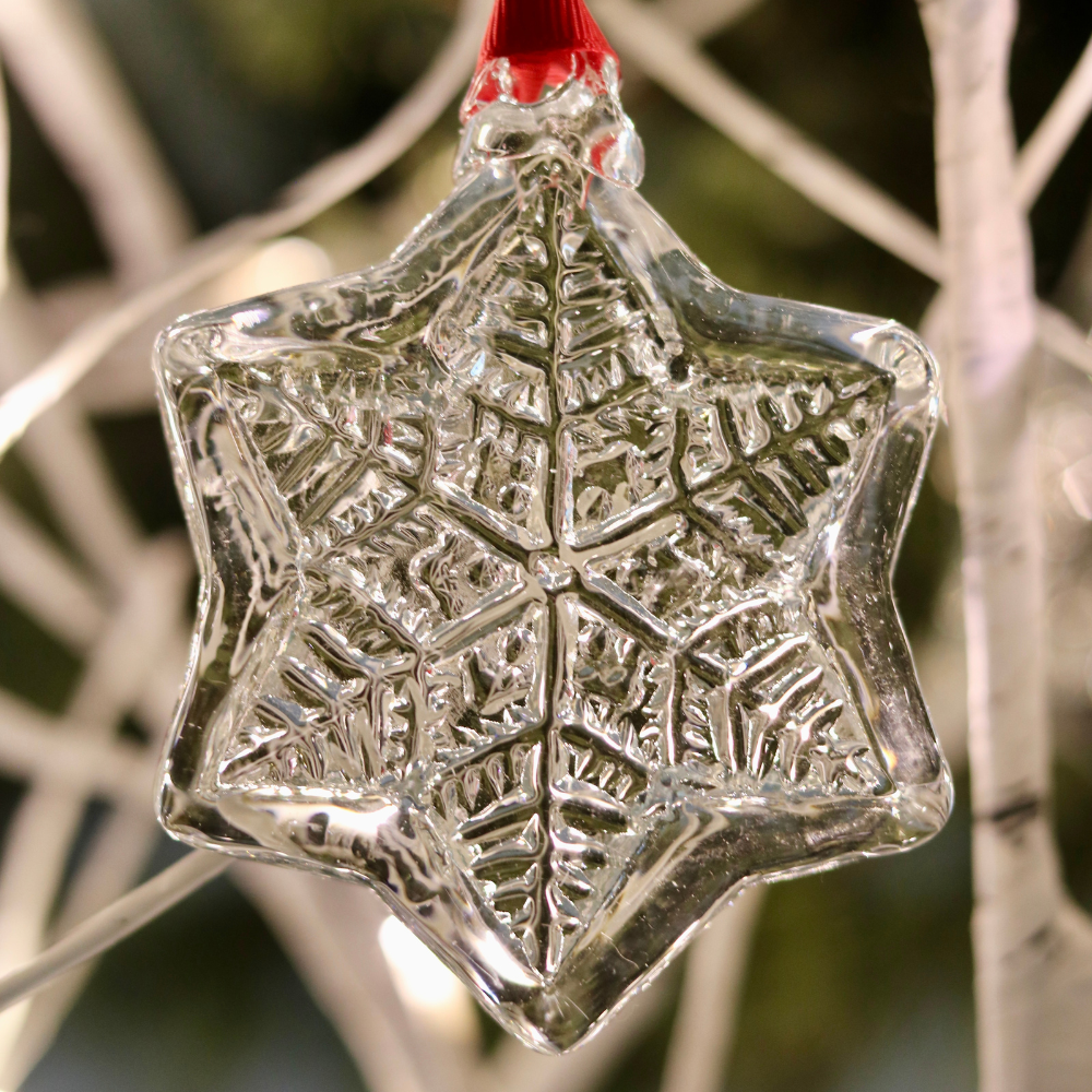 Snow jewel with a red ribbon on a white tree with twinkle lights