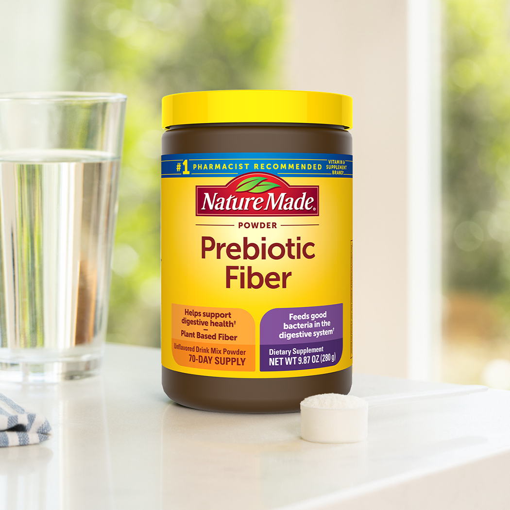 Nature Made Prebiotic Fiber tub sitting on a counter with a class of water.