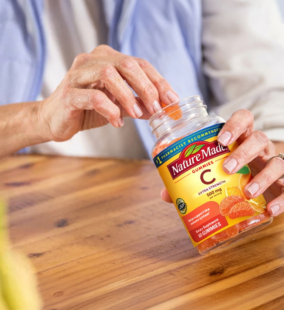 Person reaching for Nature Made Vitamin C gummies at a table.