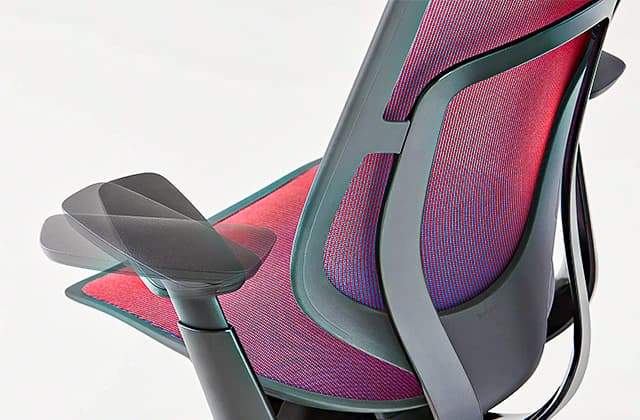 Silla de oficina Steelcase Karman en Shift Red-Blue, centrada en los reposabrazos, mostrando los reposabrazos ajustables, sobre un fondo gris.