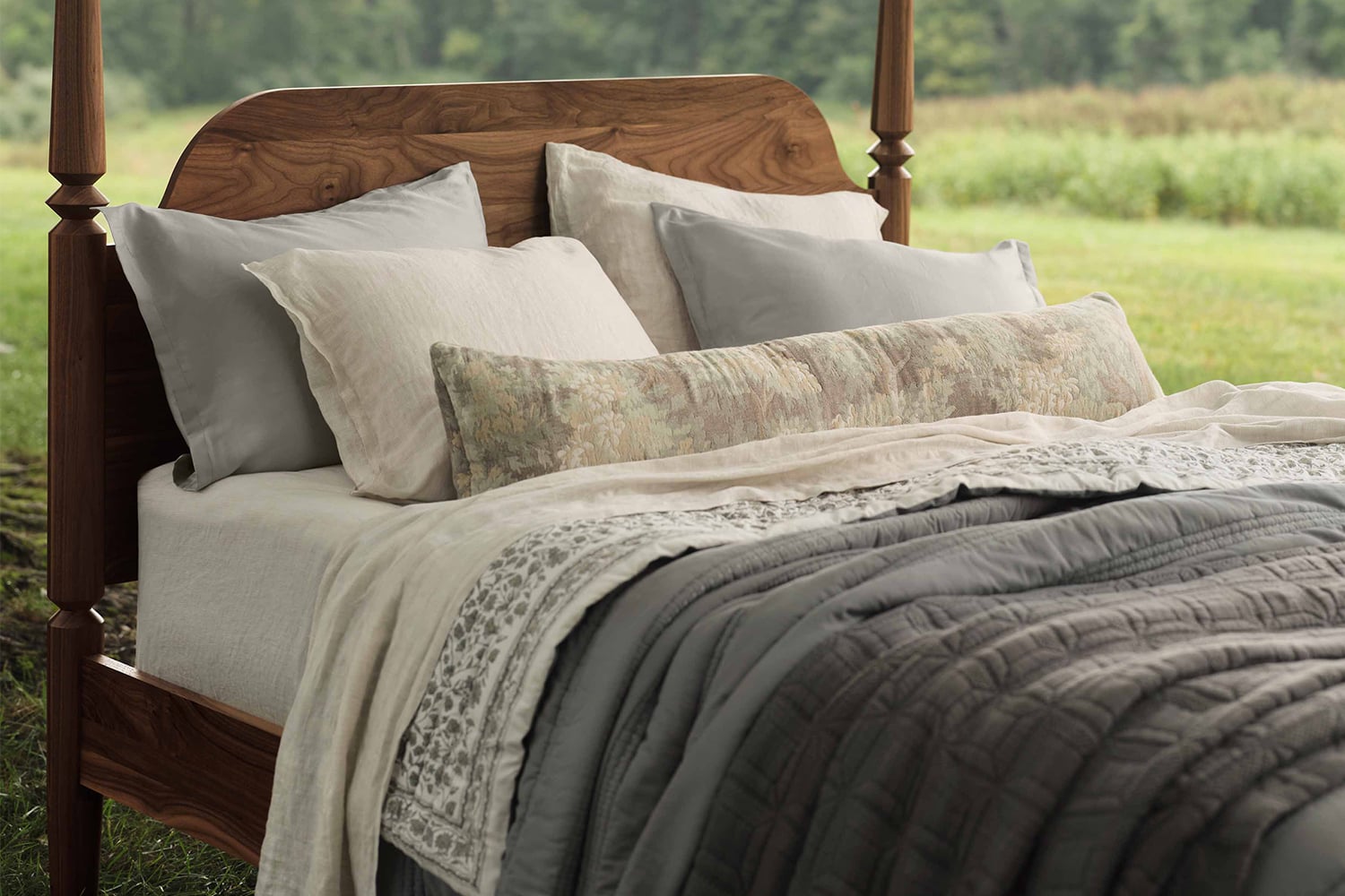 Close-up of layered linen and cotton bedding with natural wood, representing grounding materials in a feng shui bedroom