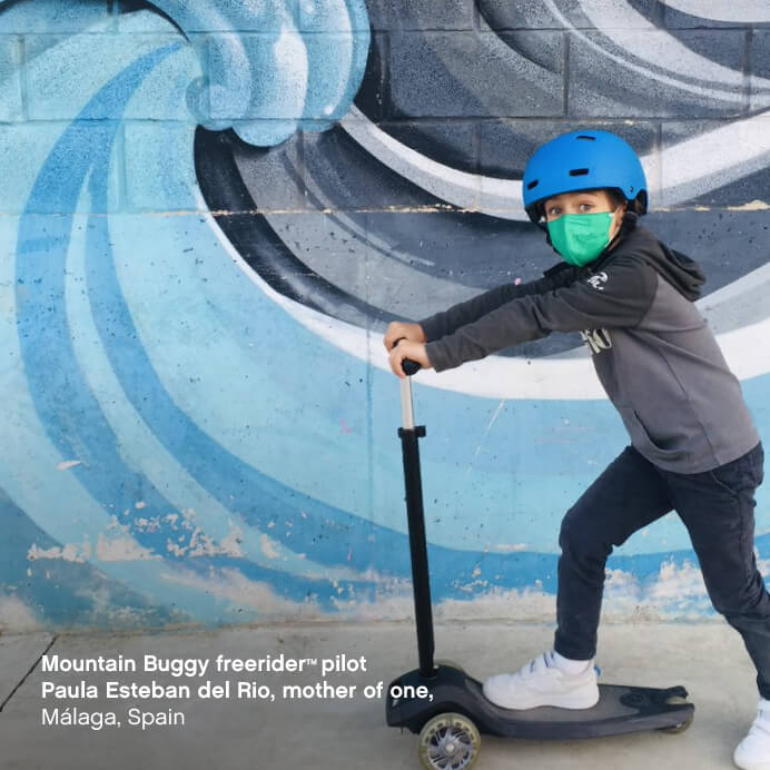 Big kid zooming around on 3 wheel scooter with his safety helmet on. Wave mural on concrete brick wall background - Mountain Buggy freerider™ pilot Paula Esteban del Reo, mother of one, Málaga, Spain
