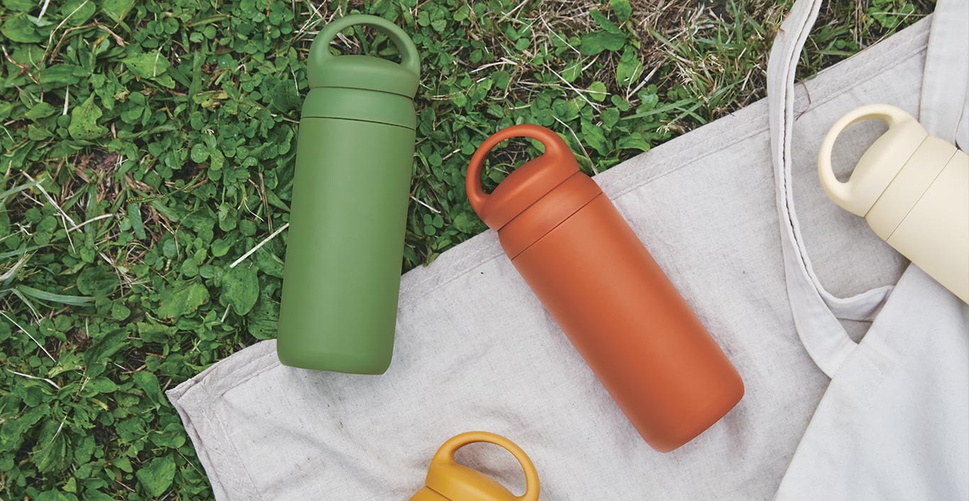  DAY OFF tumblers in green, mustard, orange, and white laid out on a blanket and grass  
