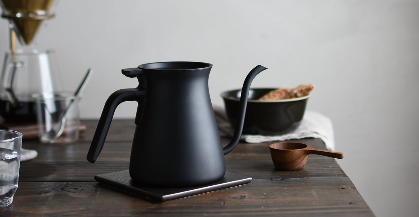  POUR OVER KETTLE black placed on a coaster with tableware  