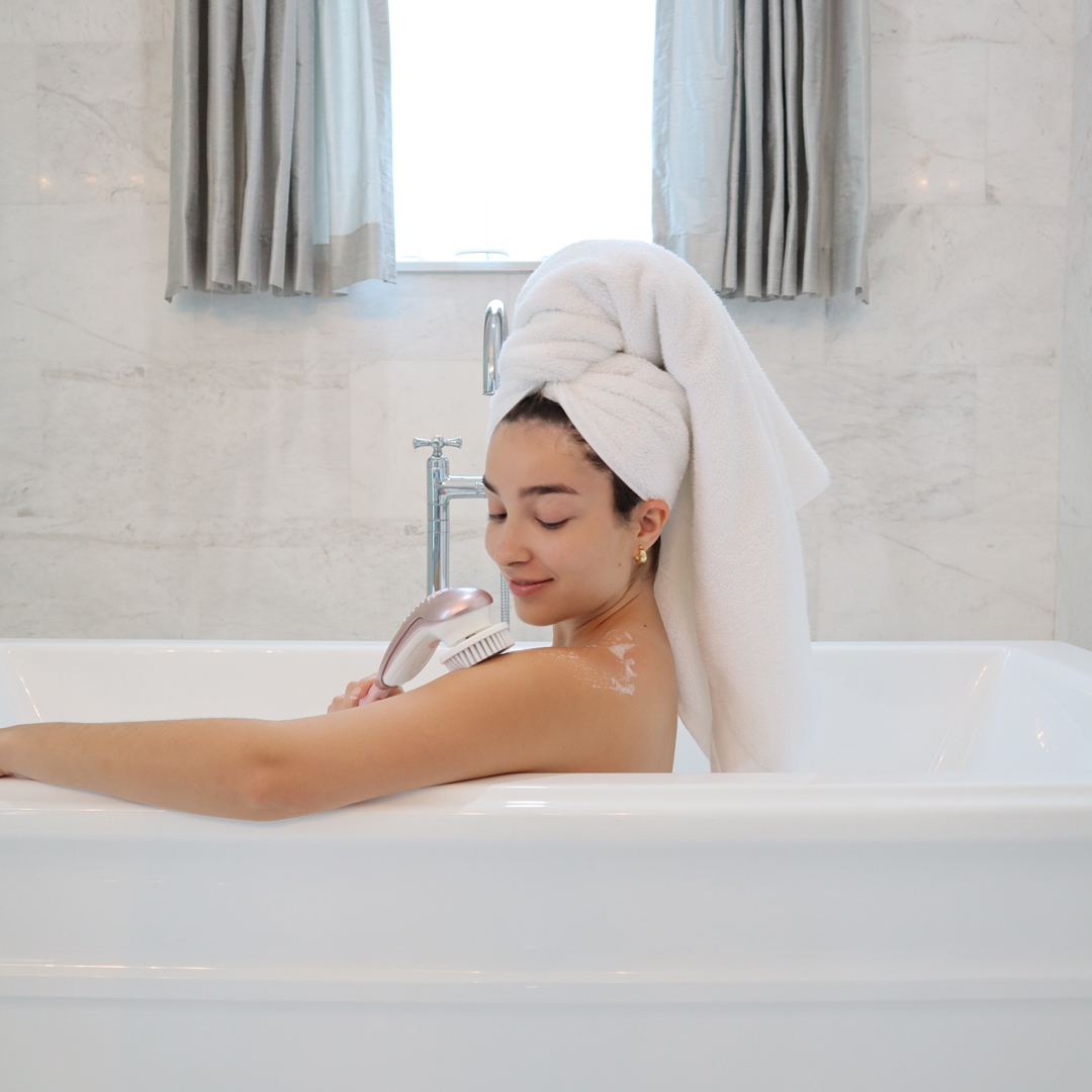 Woman using the cora 7 full body spin brush in the bath