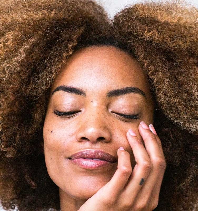 Woman rests her face in her hands as she shuts her eyes