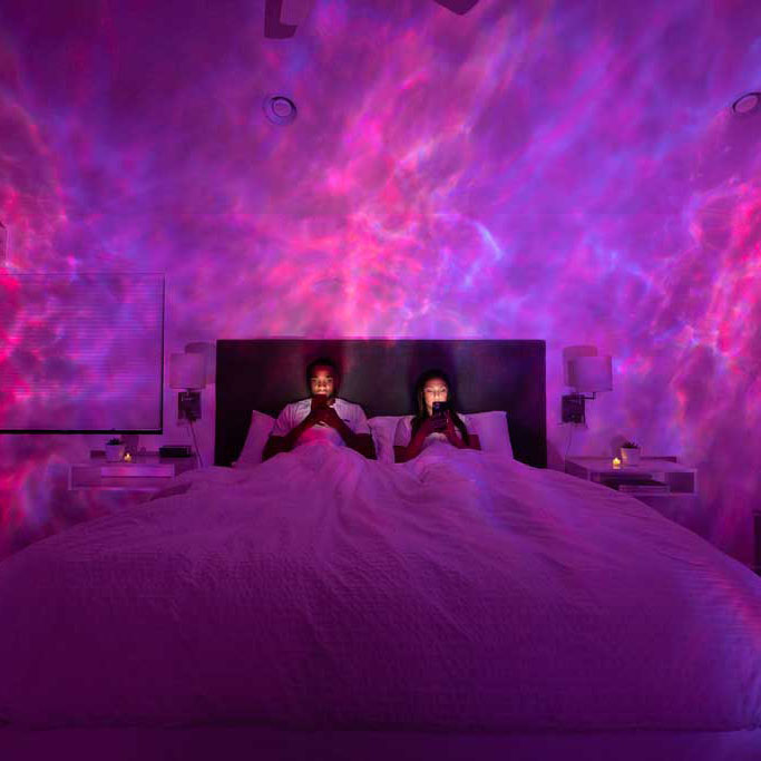 couple reading in bed with pink galaxy lights