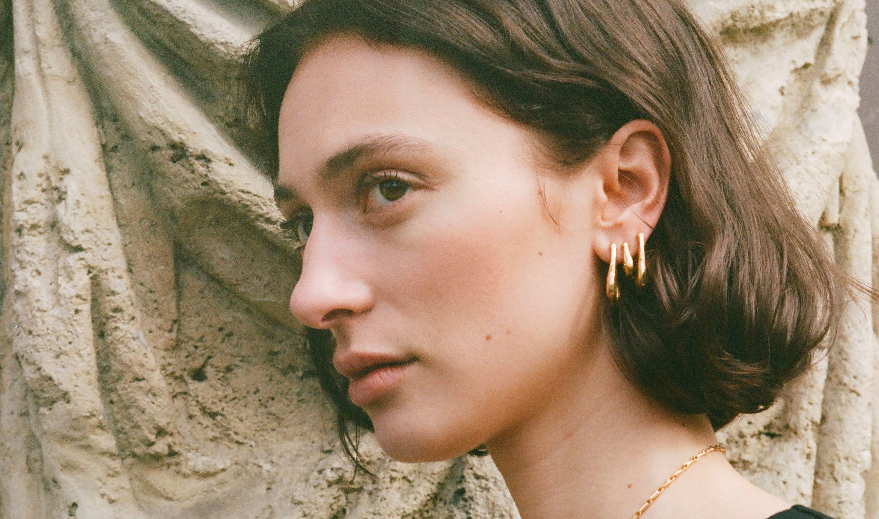 Woman wearing gold hoop earrings by Alighieri