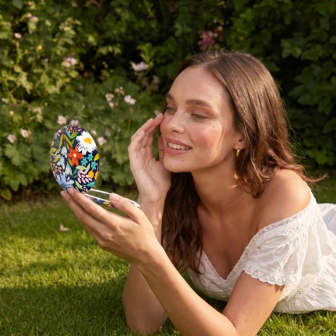 Happy Flowers Mini Taylor Lighted Compact by Fancii gazed into by woman in a garden
