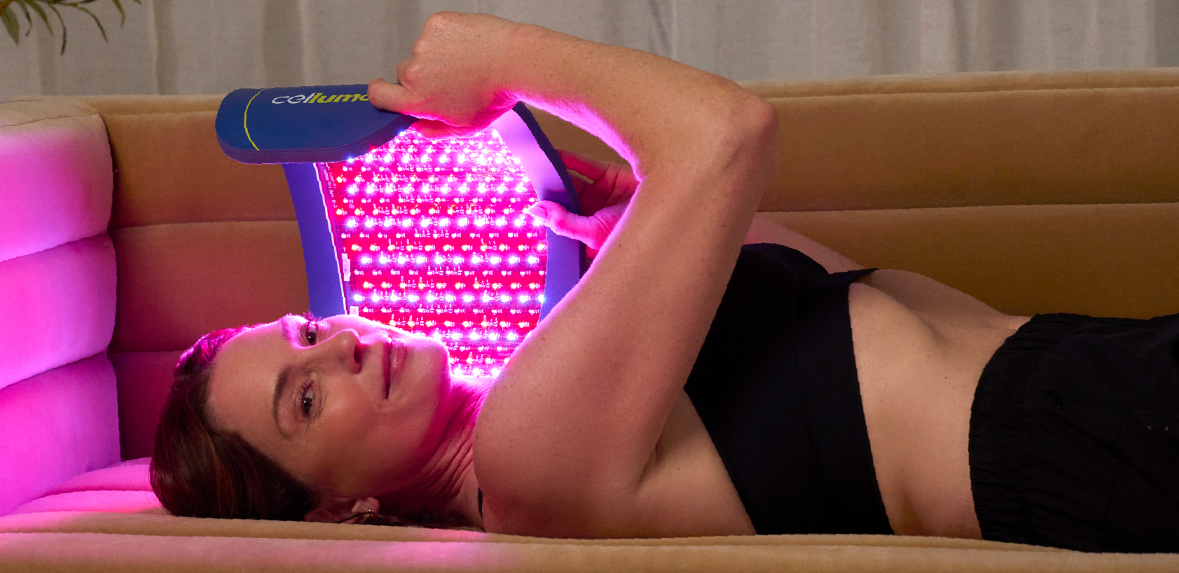 A woman lying on the floor at her house using a Celluma PRO for an at-home LED light therapy treatment