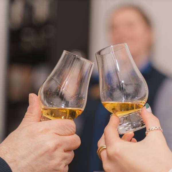 Two people toasting drams of whisky.