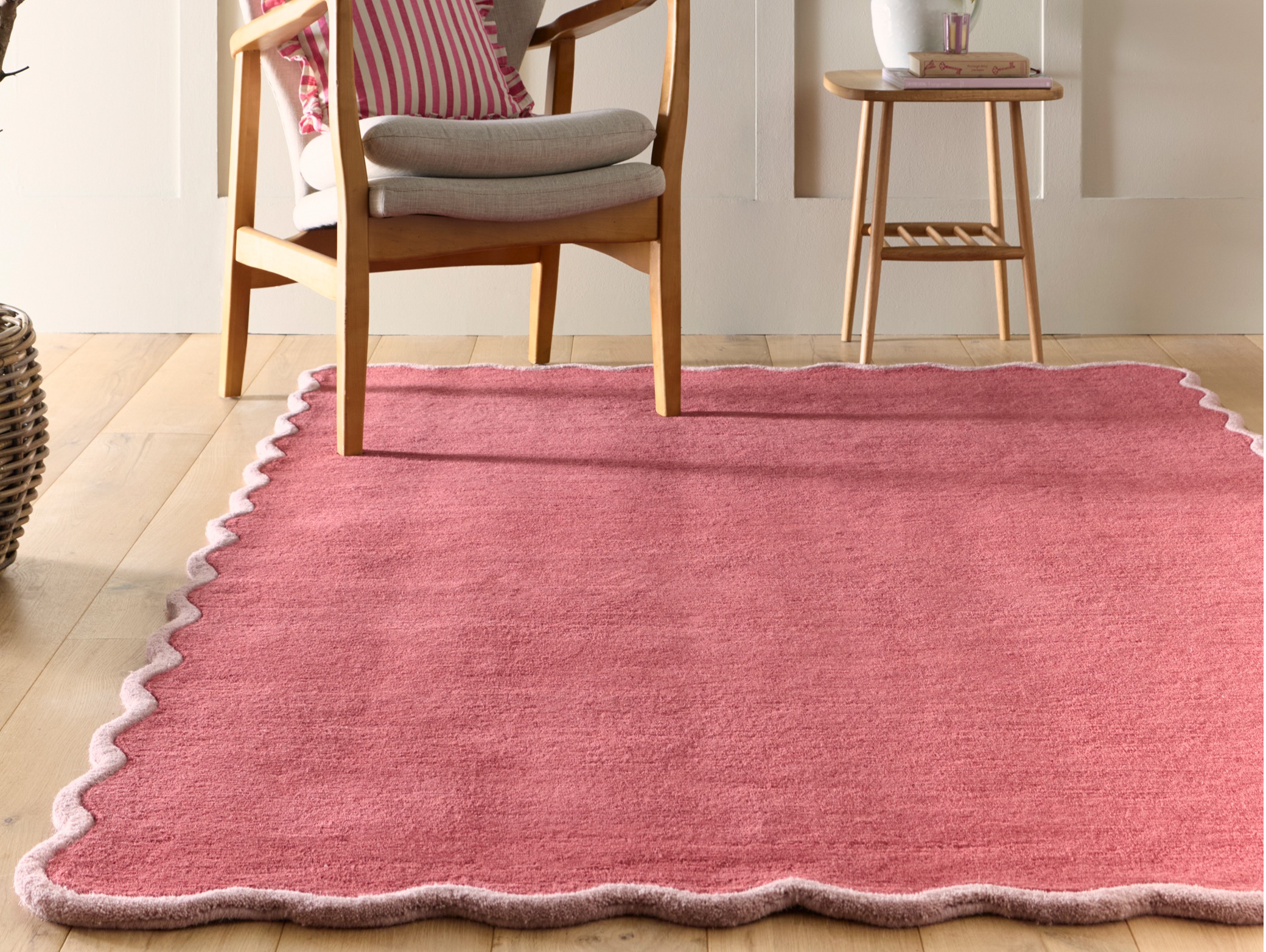 Scalloped Elsie Coral/Lilac Wool Rug, styled on wooden flooring.